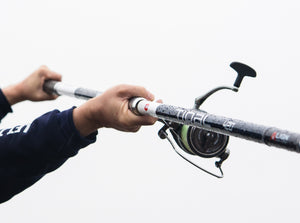 Close up of the hands of an angler holding a PENN Tidal fishing rod with a blurred background