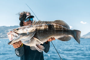 PENN Fisherman displaying a beautifully large Grouper that has been caught. With rod, water and sky in the background